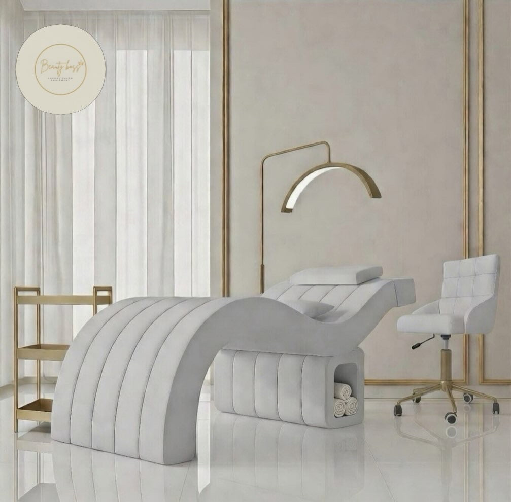 Modern massage room with gray massage table, white chair, and gold accents.