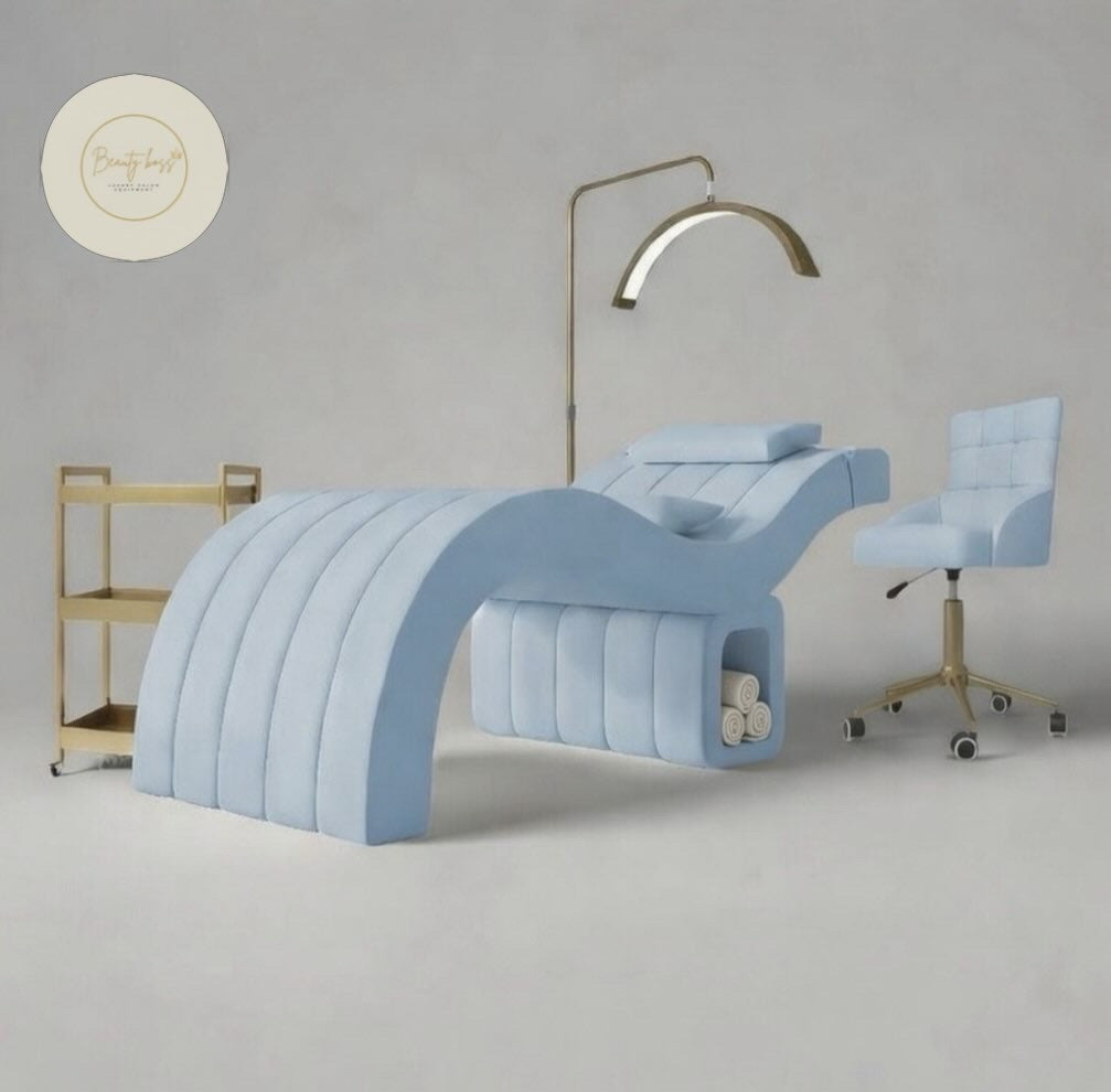 Modern light blue salon chair with matching armchair and gold stand against a gray background.