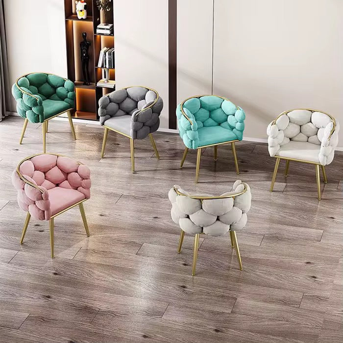 Set of colorful armchairs with tufted backs on a wooden floor.